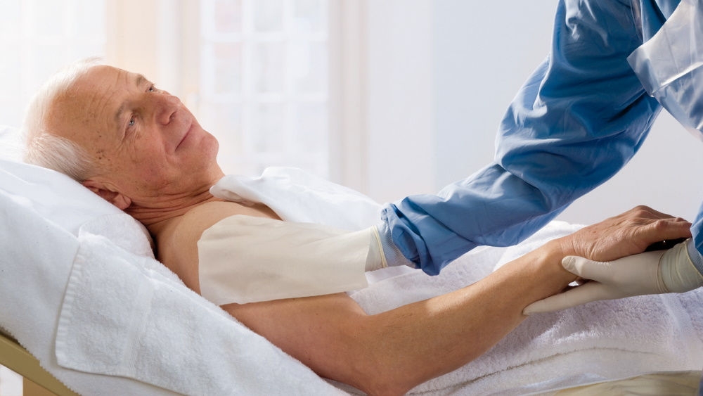 Patient in hospital bed. Nurse decolonizes the patient's upper arm with a cloth .