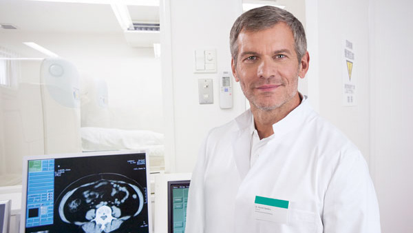 A male healthcare professional standing next to a medical device